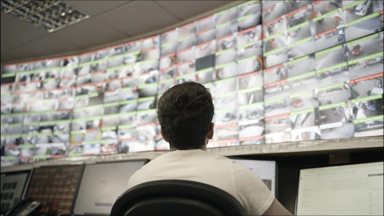 An operator at a control-room video wall showing dozens of live camera feeds, each labeled with its location.