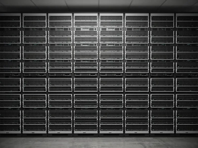 A wall of storage in a data hall, running floor to ceiling and the full width of the room, every bay filled with identical drive carriers