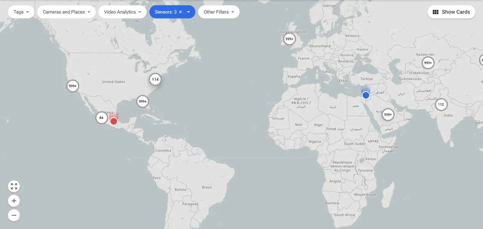 The IREX map on the world view with the Sensors filter active: clustered device pins carrying count badges such as 999+, 114, 84 and 112 across North America, Europe, Africa and Asia, above the filter chips Tags, Cameras and Places, Video Analytics, Sensors and Other Filters